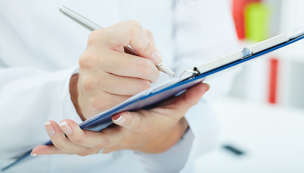Closeup of someone writing something on a clipboard